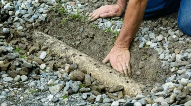 french drain installation near Cleveland Ohio clearing away top layer of French drain installation near Cleveland to fix clogged drainage pipe